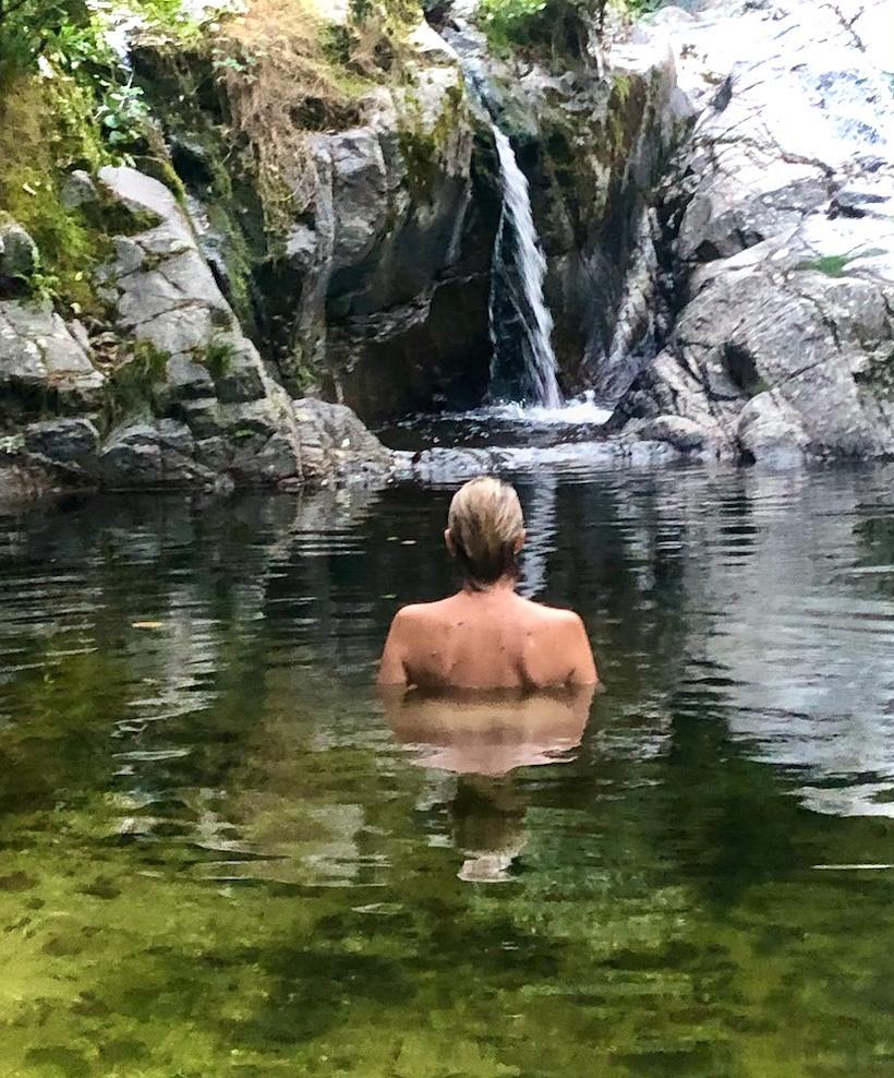 Une baigneuse dans la vasque d'eau vive au pied de la cascade