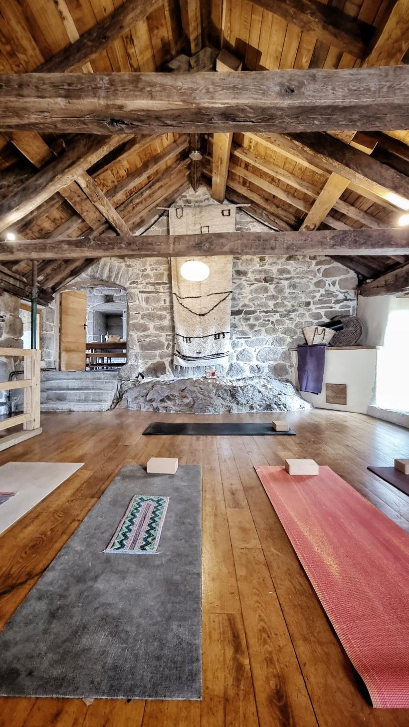 La salle de pratique sous charpente, tapis de yoga déroulés sur le parquet