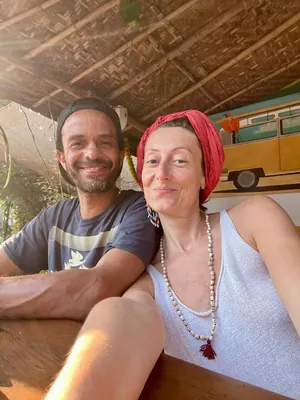 Marie-Laure et Brice souriants sous un toit de paille, au soleil
