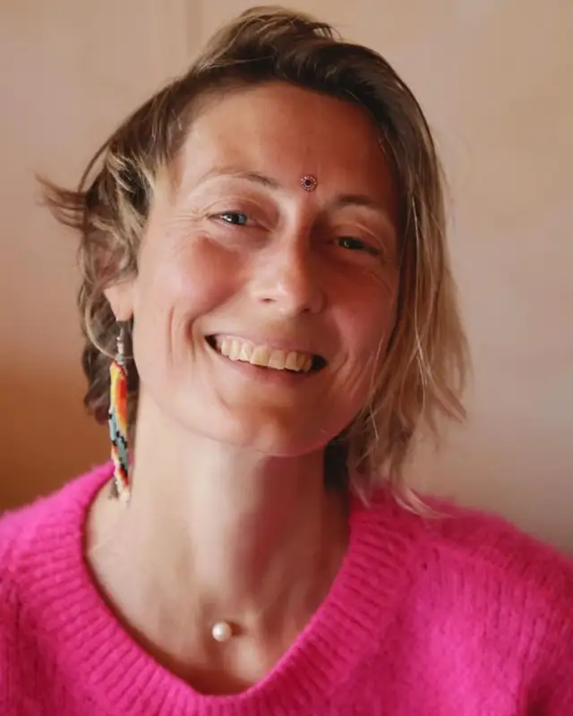 Portrait de Marie-Laure, souriante, en pull rose